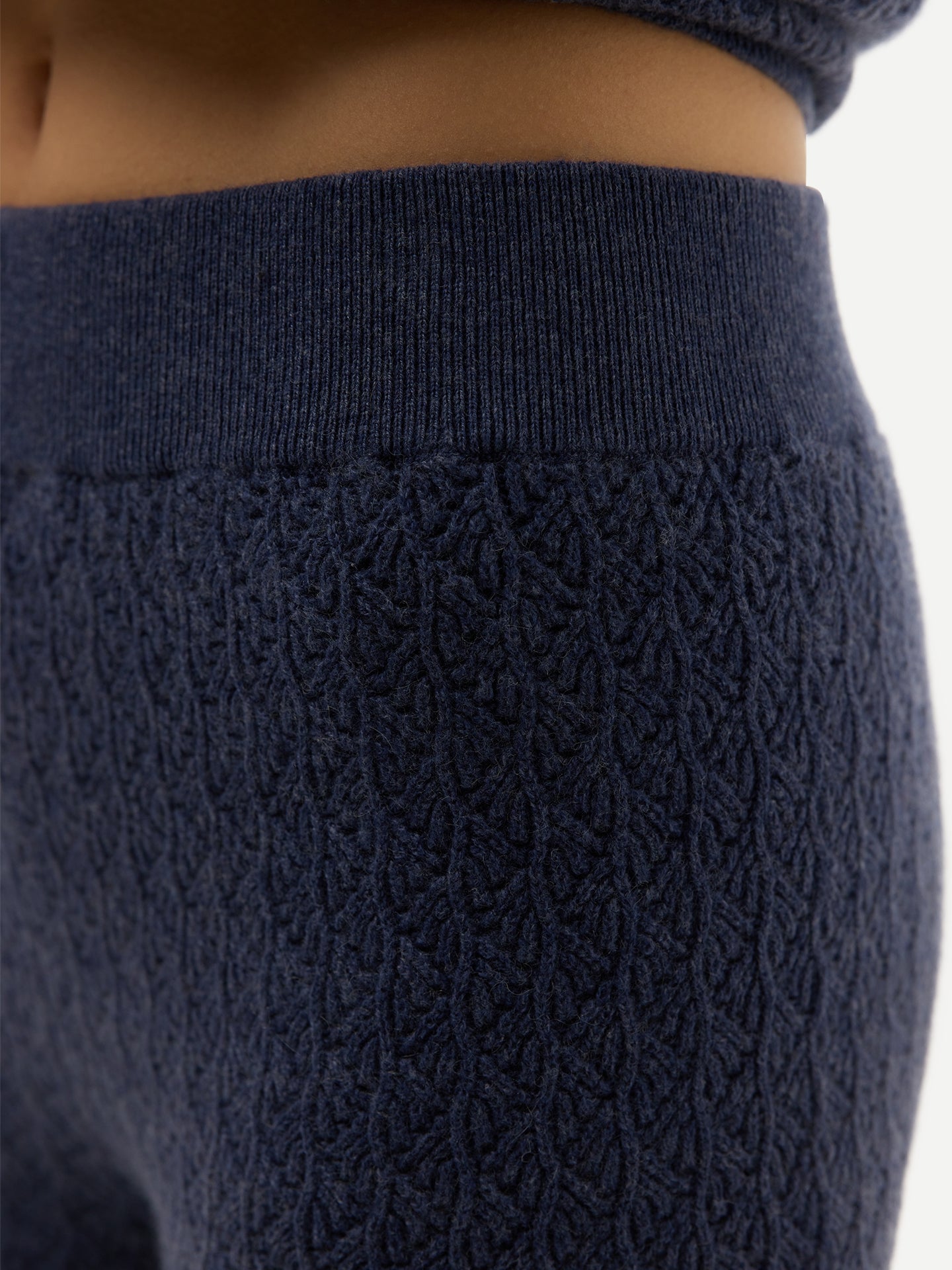 Gros plan sur un pantalon large bleu côtelé sur fond gris clair. #color_bleu-couronne