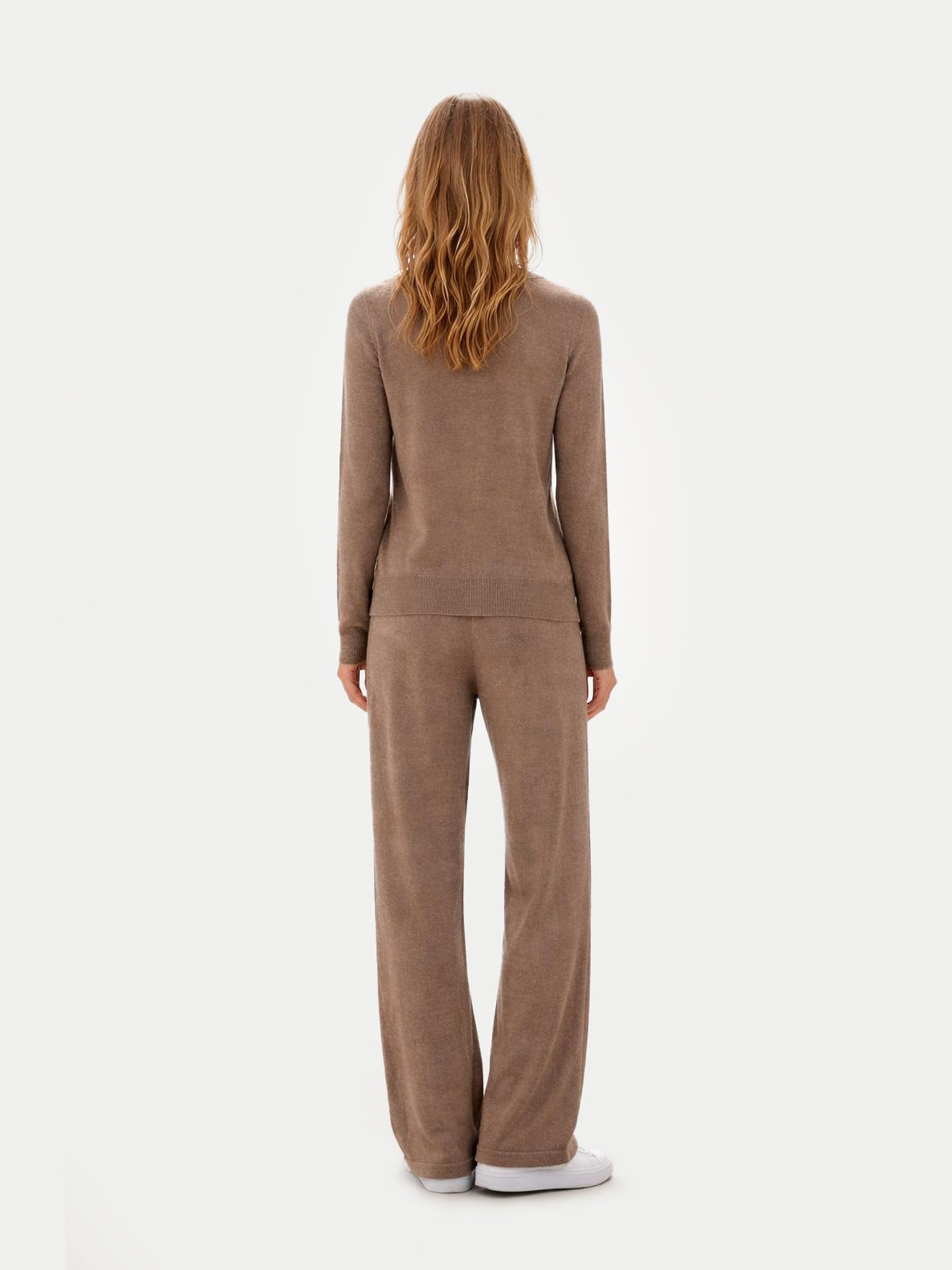 Vue de dos d'une femme portant un pull marron à col rond assorti à un pantalon à jambes larges sur un fond gris clair. #color_taupe