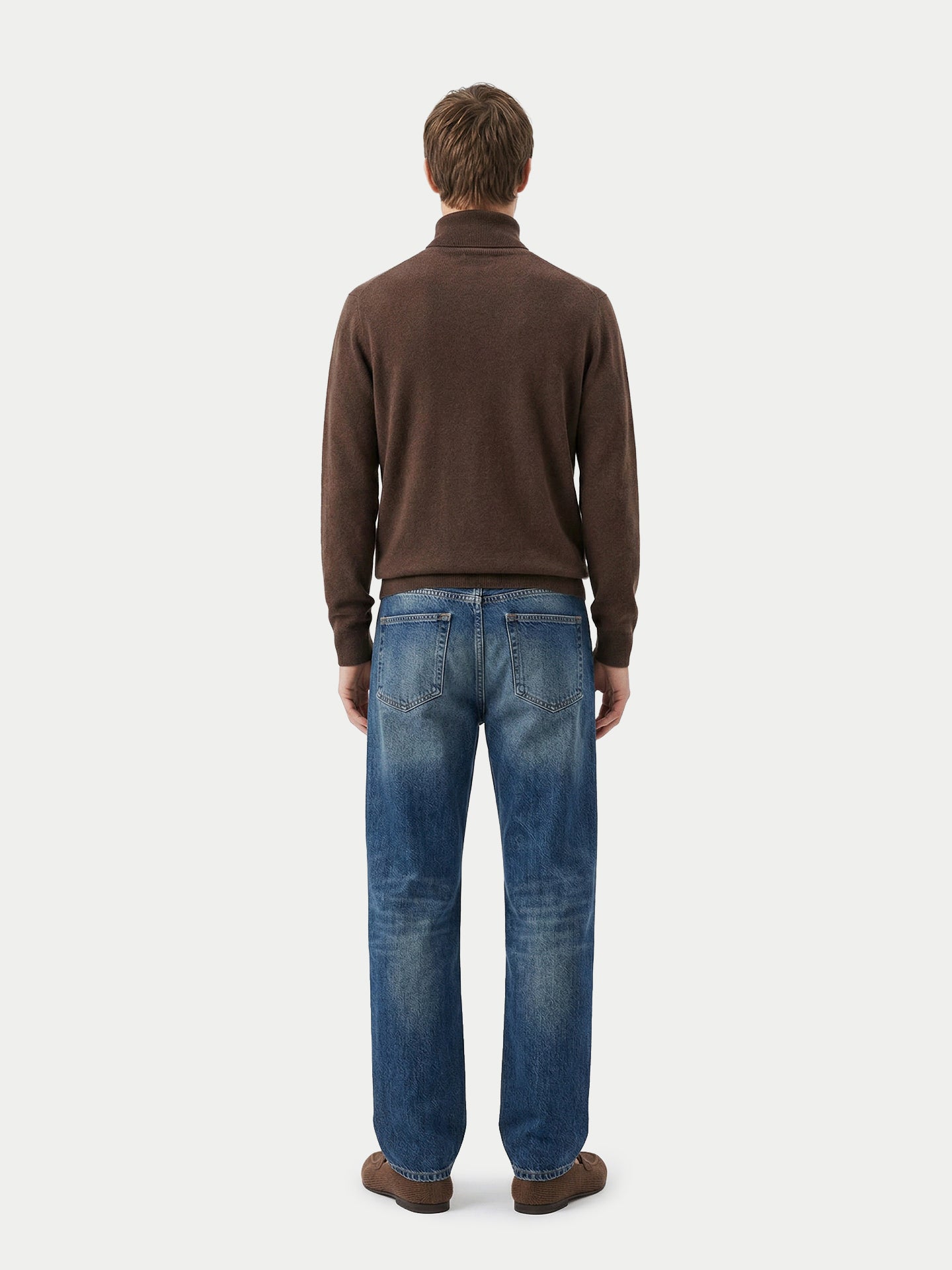 Vue de dos d'un homme portant un pull à col roulé marron et un jean bleu sur fond gris clair. #color_cacao