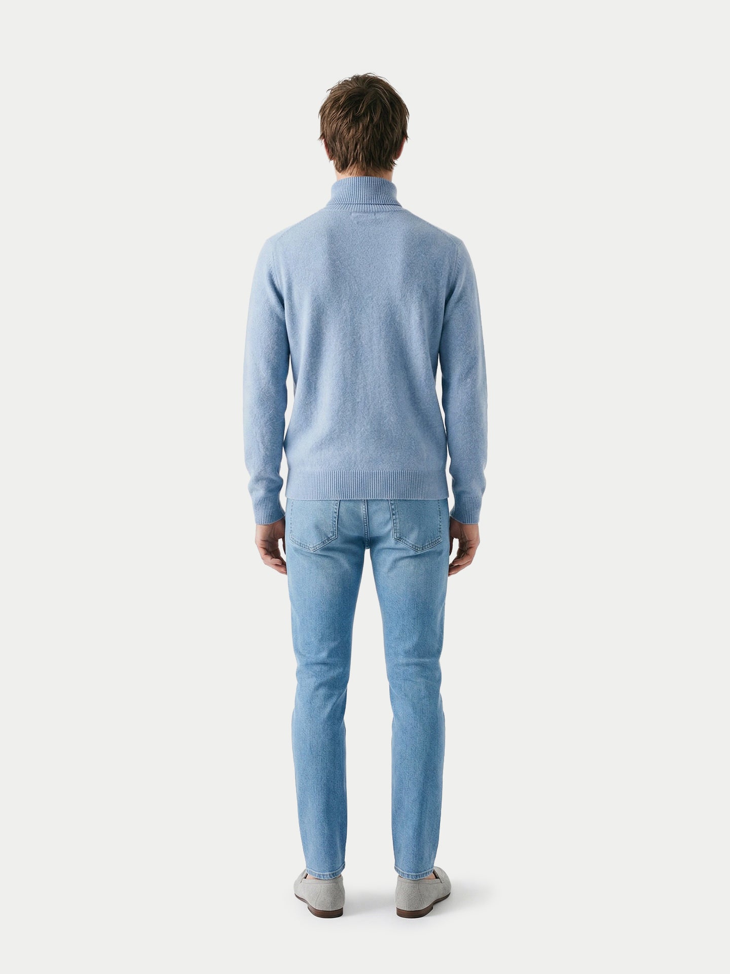 Vue de dos d'un homme portant un pull à col roulé bleu clair et un jean sur fond gris clair. #color_bleu-clair