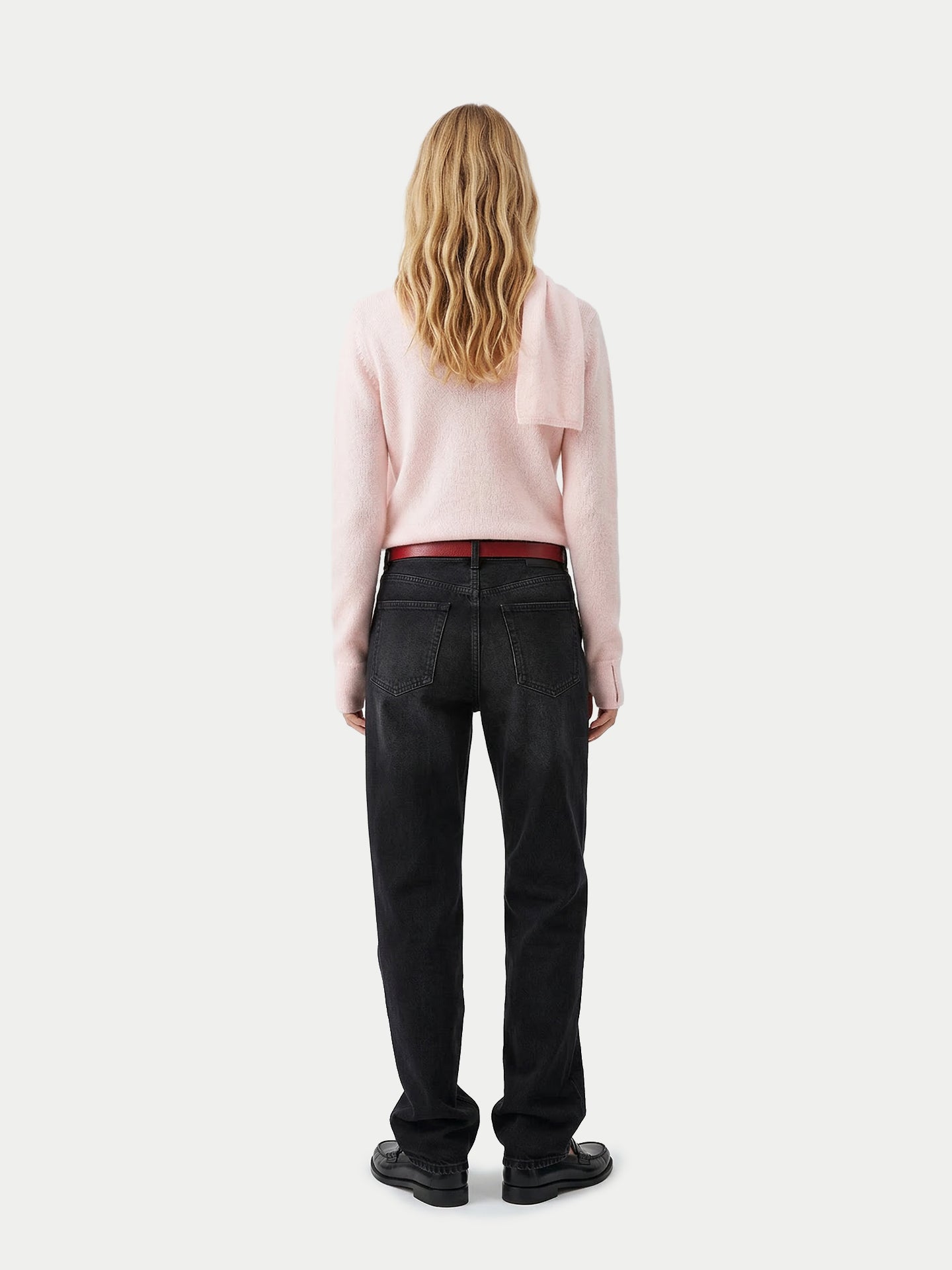 Vue de dos d'une femme portant un pull rose avec une écharpe intégrée, un jean noir et des mocassins noirs sur un fond gris clair. #color_peach-blush