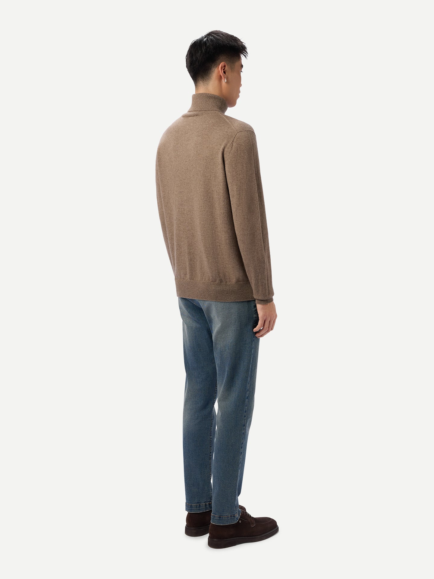 Vue de dos d'un homme portant un pull à col roulé beige et un jean bleu sur fond gris clair. #color_taupe