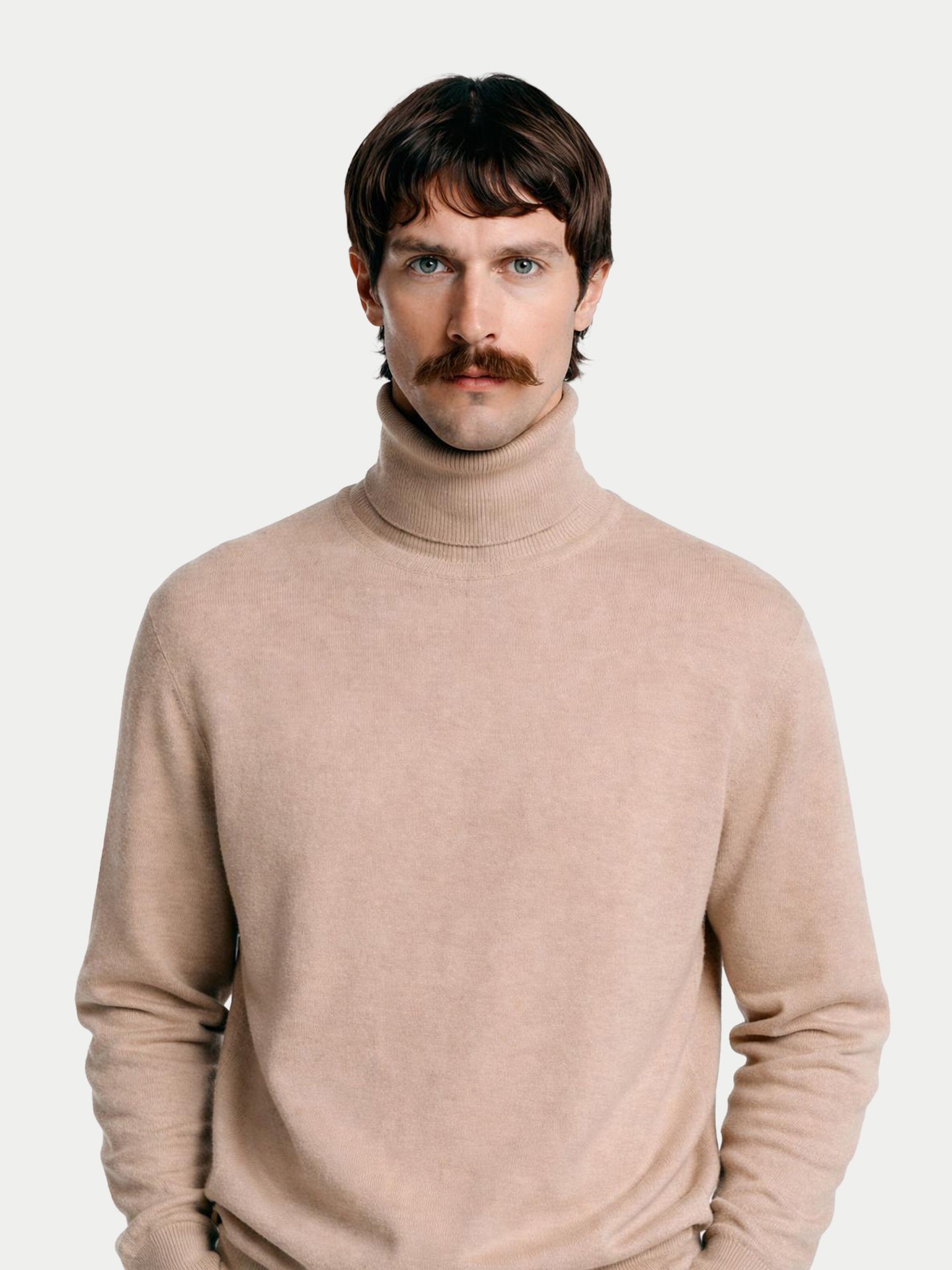 Gros plan de face d'un homme portant un pull à col roulé beige sur fond gris clair. #color_beige