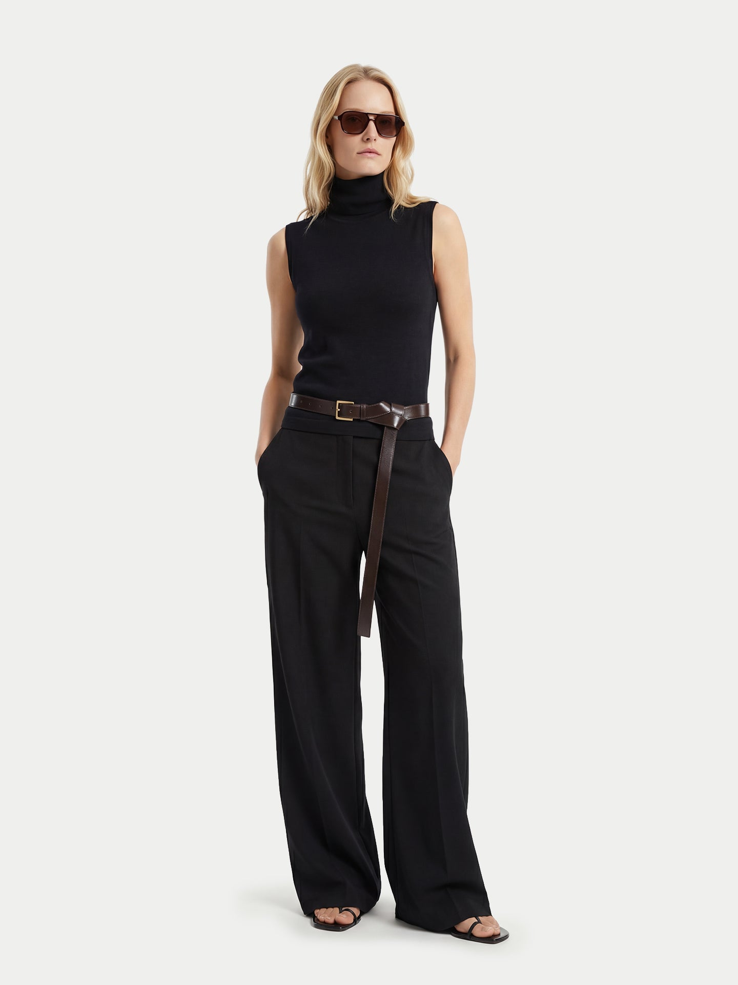 Vue de face d'une femme portant un haut en cachemire noir sans manches à col roulé assorti à un pantalon large, sur fond gris clair. #color_noir