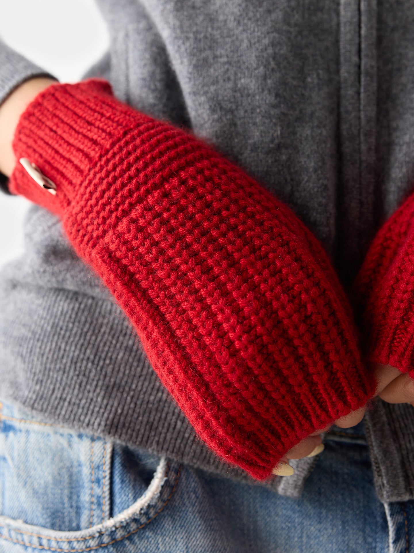 Gros plan de face d'une femme portant des gants rouges côtelés sans doigts sur fond gris clair. #color_piment