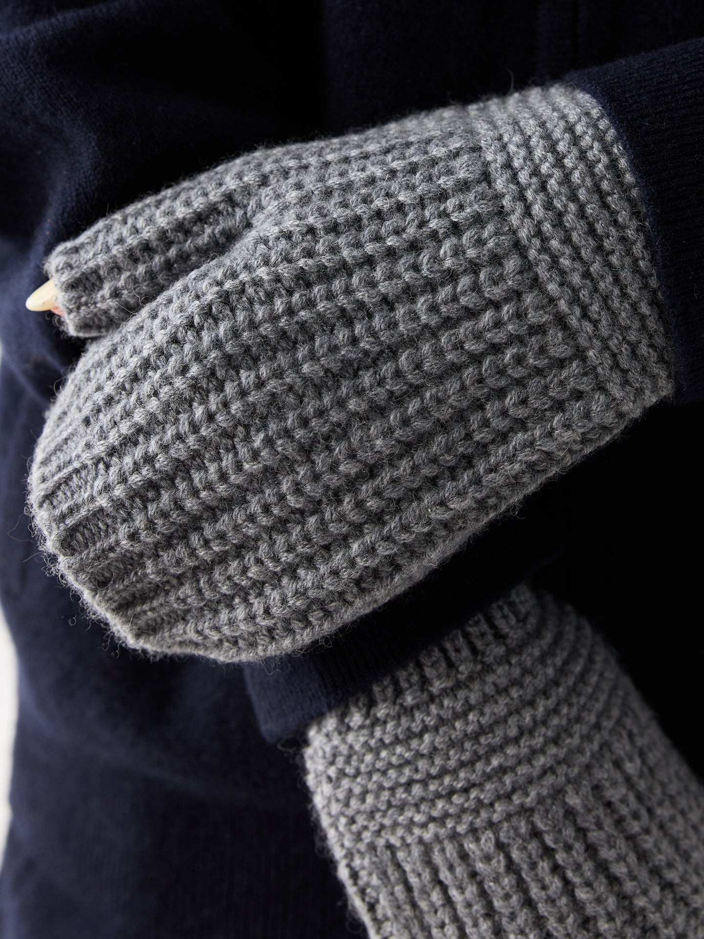 Gros plan de face d'une femme portant des gants gris côtelés sans doigts sur fond gris clair. #color_gris-foncé