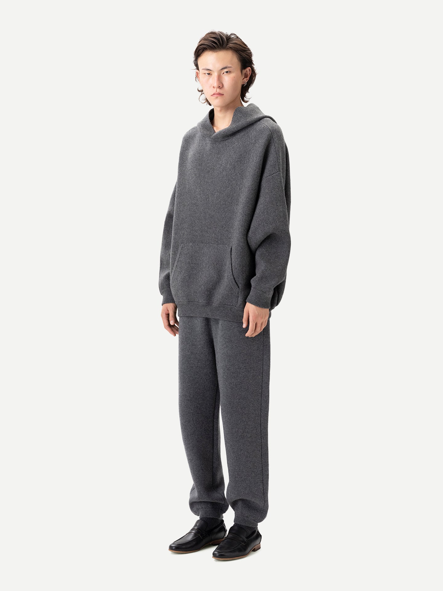 Vue de profil d'un homme portant un ensemble sweat à capuche et jogging gris assortis sur fond gris clair. #color_plum-kitten