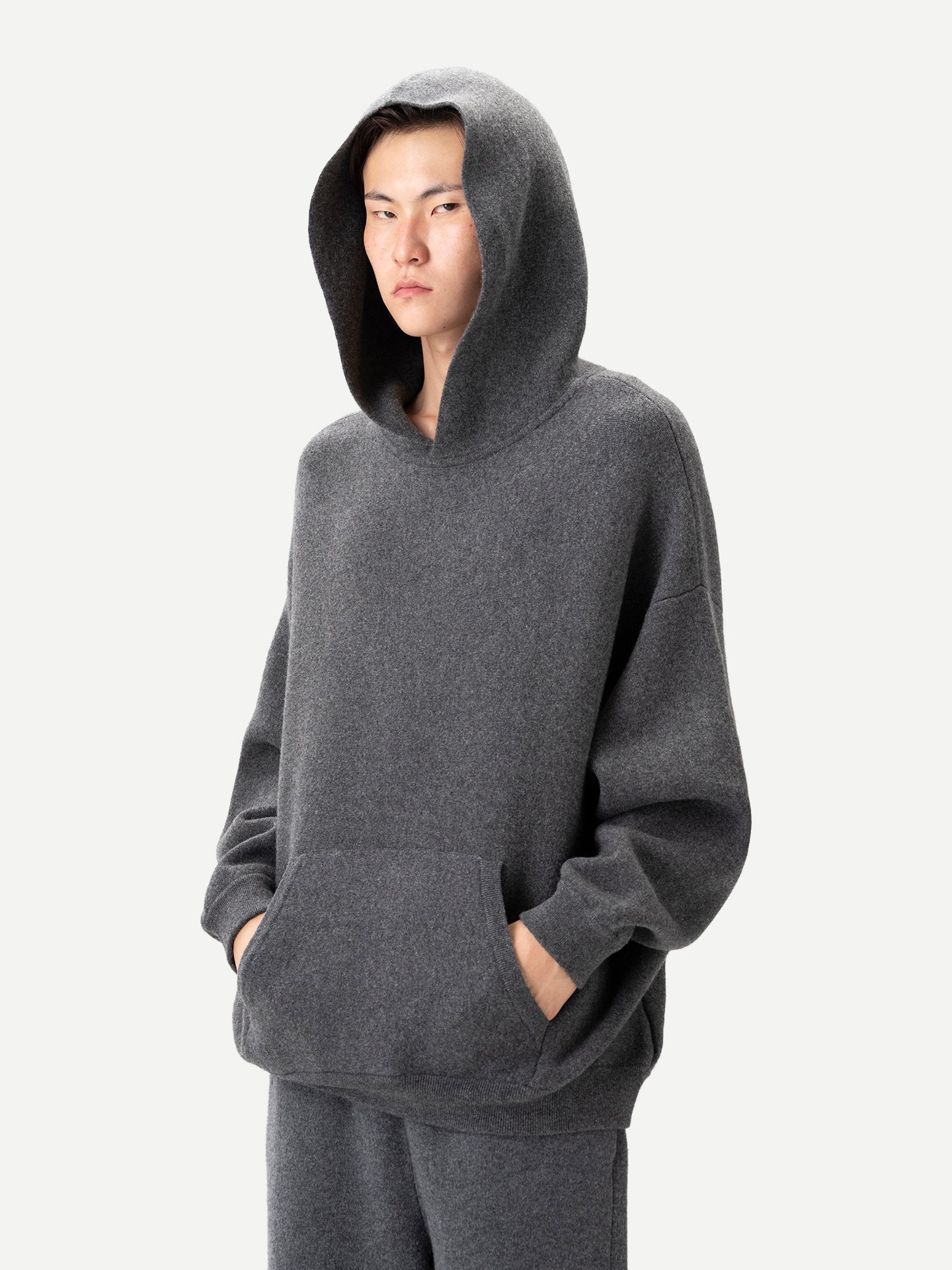 Gros plan de profil d'un homme portant un sweat à capuche gris avec poche sur fond gris clair. #color_plum-kitten