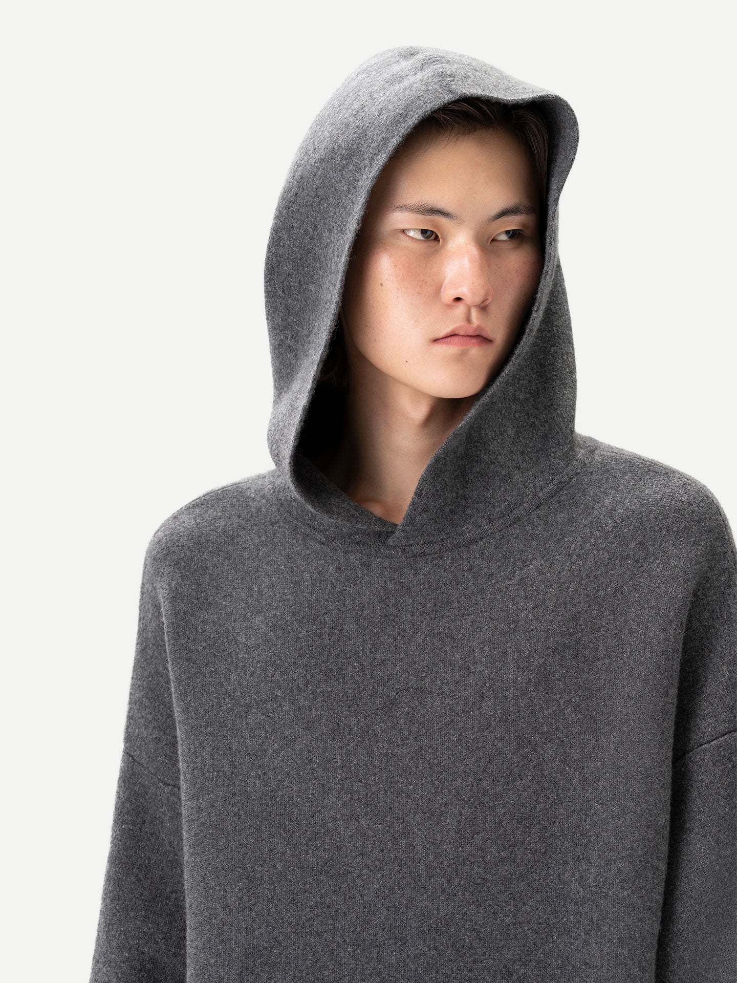 Gros plan de face d'un homme portant un sweat à capuche gris sur fond gris clair. #color_plum-kitten