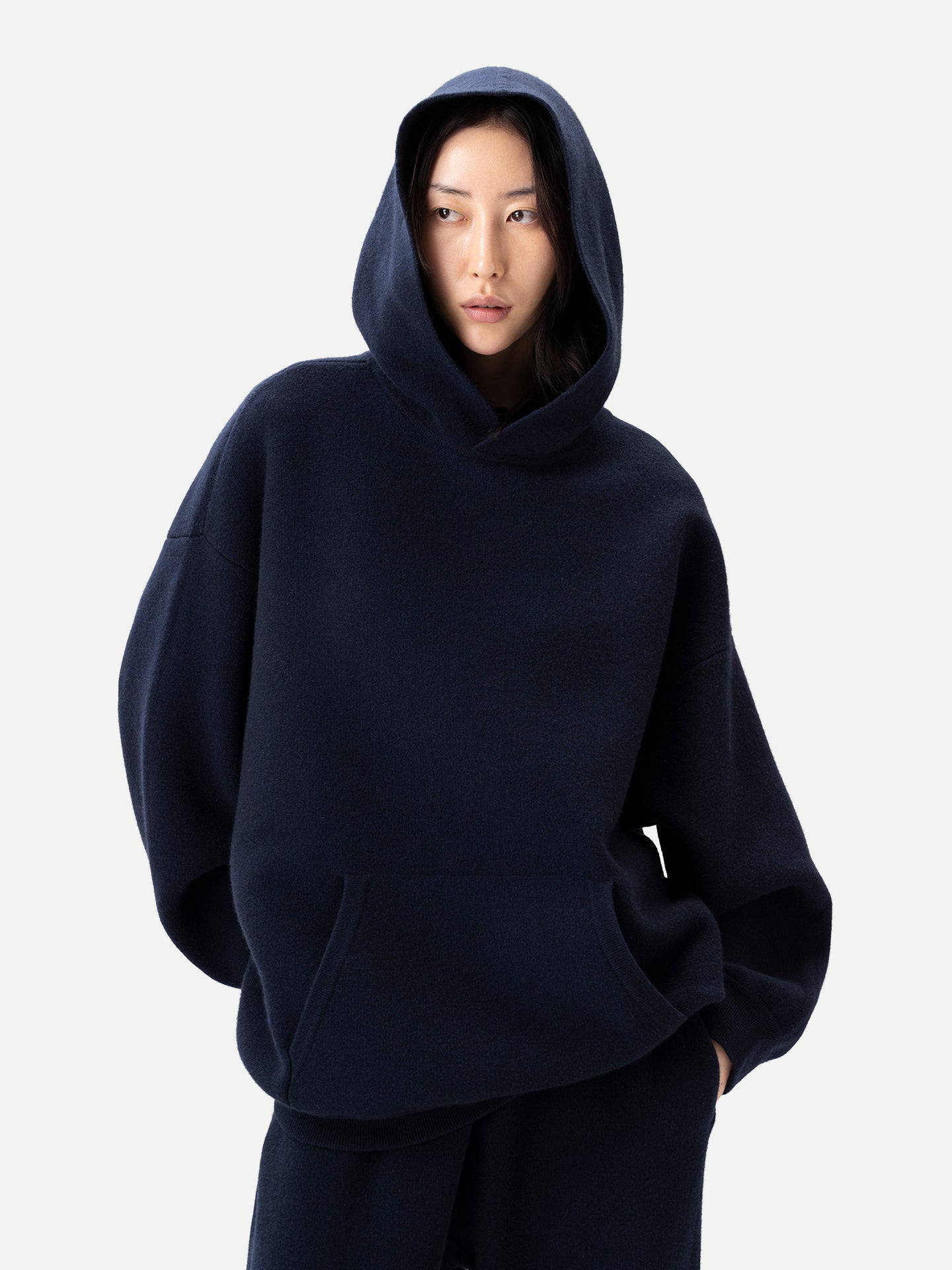 Gros plan de face d'une femme portant un ensemble sweat-shirt et pantalon bleu marine assortis sur fond gris clair. #color_india-ink