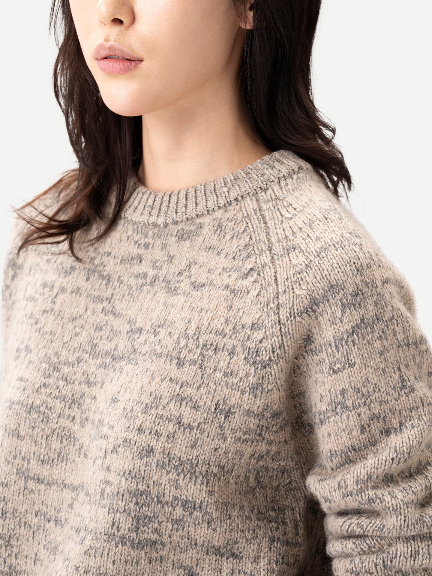 Gros plan sur une femme portant un pull à col rond côtelé beige-taupe sur fond gris clair. #color_oxfor-tan