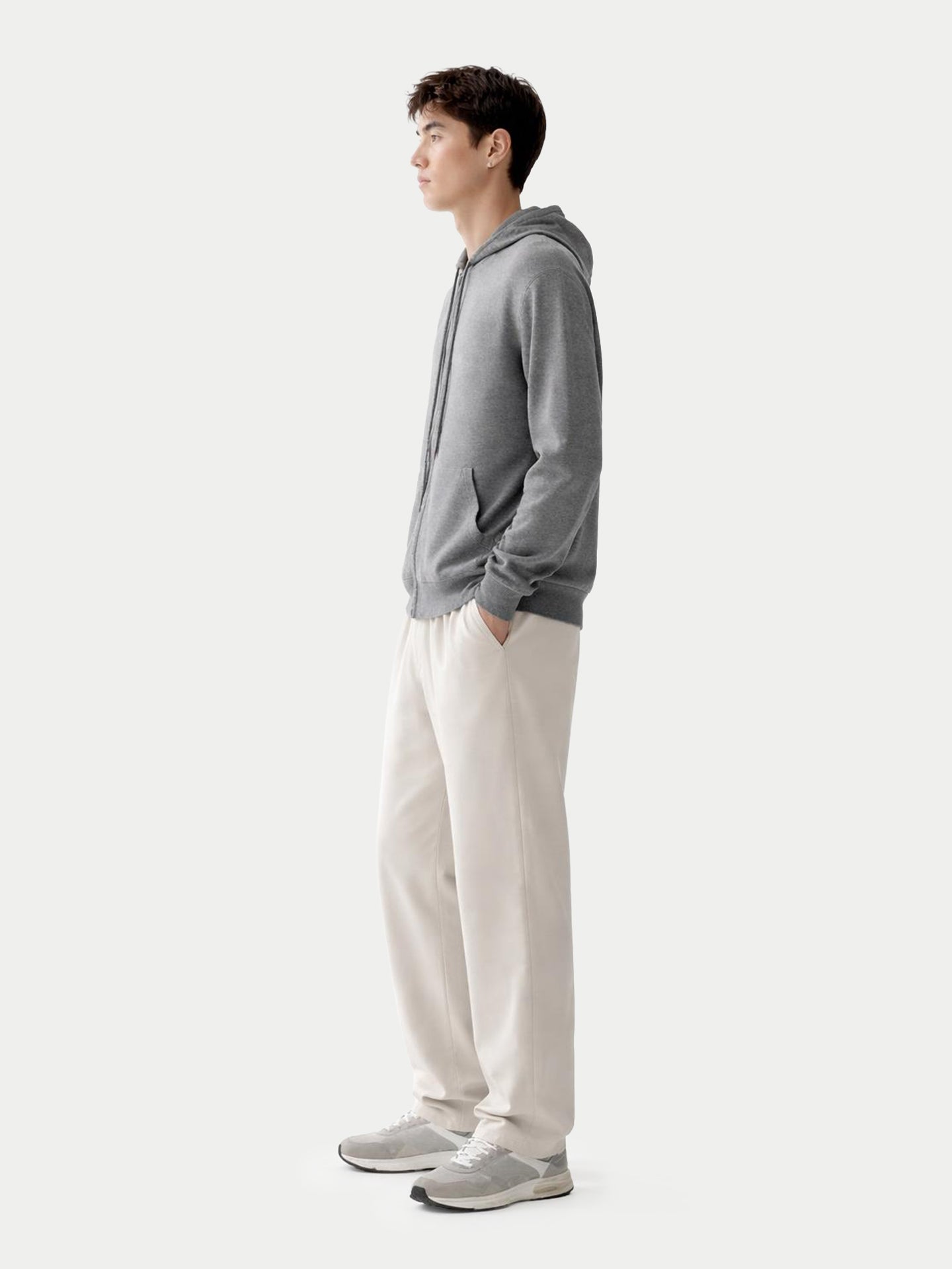 Vue de profil d'un sweat à capuche gris zippé et d'un pantalon blanc sur fond gris clair. #color_gris-foncé