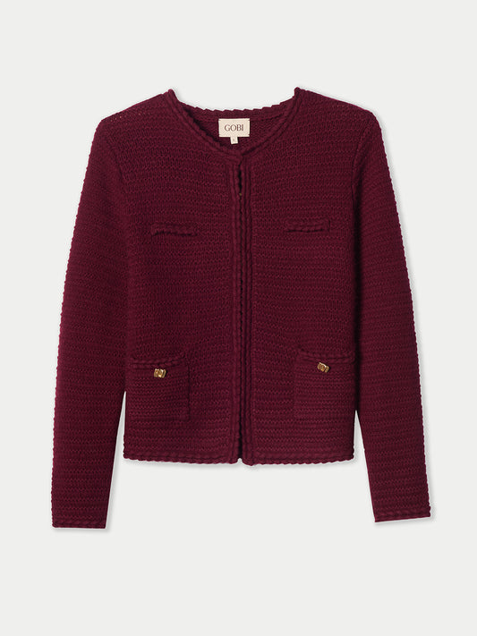 Vue de face d'un cardigan bordeaux en maille à col rond, avec poches poitrine et taille, bouton doré sur les poches latérales, sur fond gris clair. #color_Zindanfil