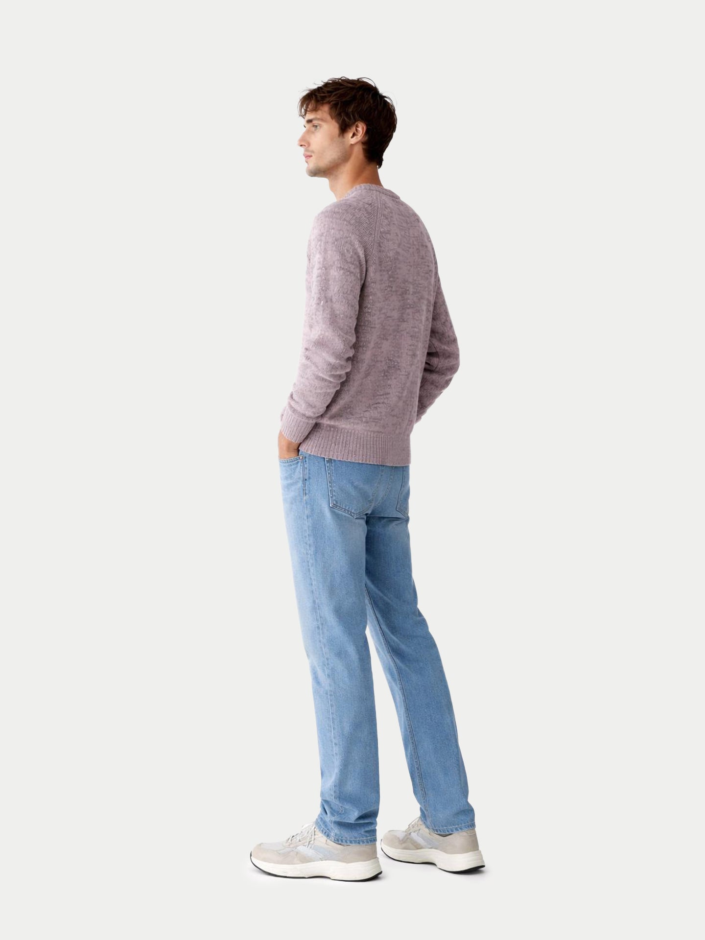 Vue de dos d'un homme portant un pull à col rond rose-gris et un jean bleu sur fond gris clair. #color_rose-ivoire