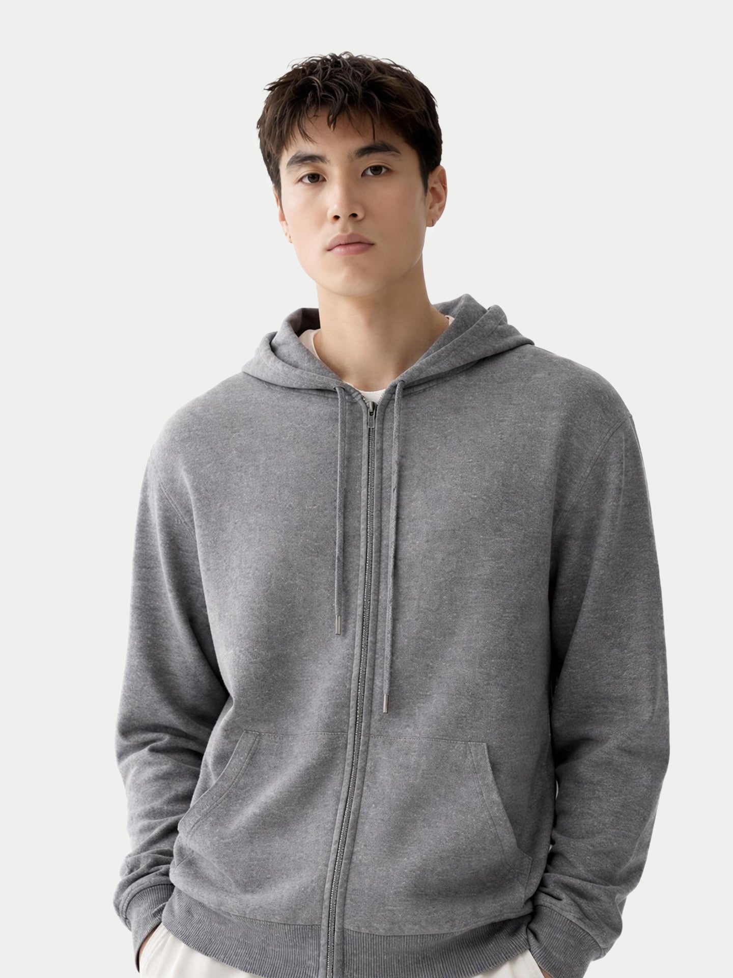 Gros plan de face d'un sweat à capuche gris zippé avec poches latérales sur fond gris clair. #color_gris-foncé