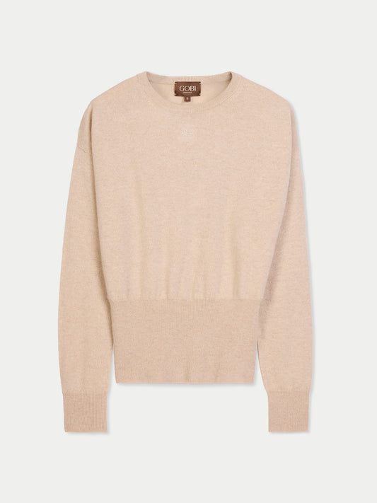 Vue de face d'un pull beige à manches longues, avec poignets et taille côtelés et un petit logo de marque en haut sur fond gris clair. #color_beige