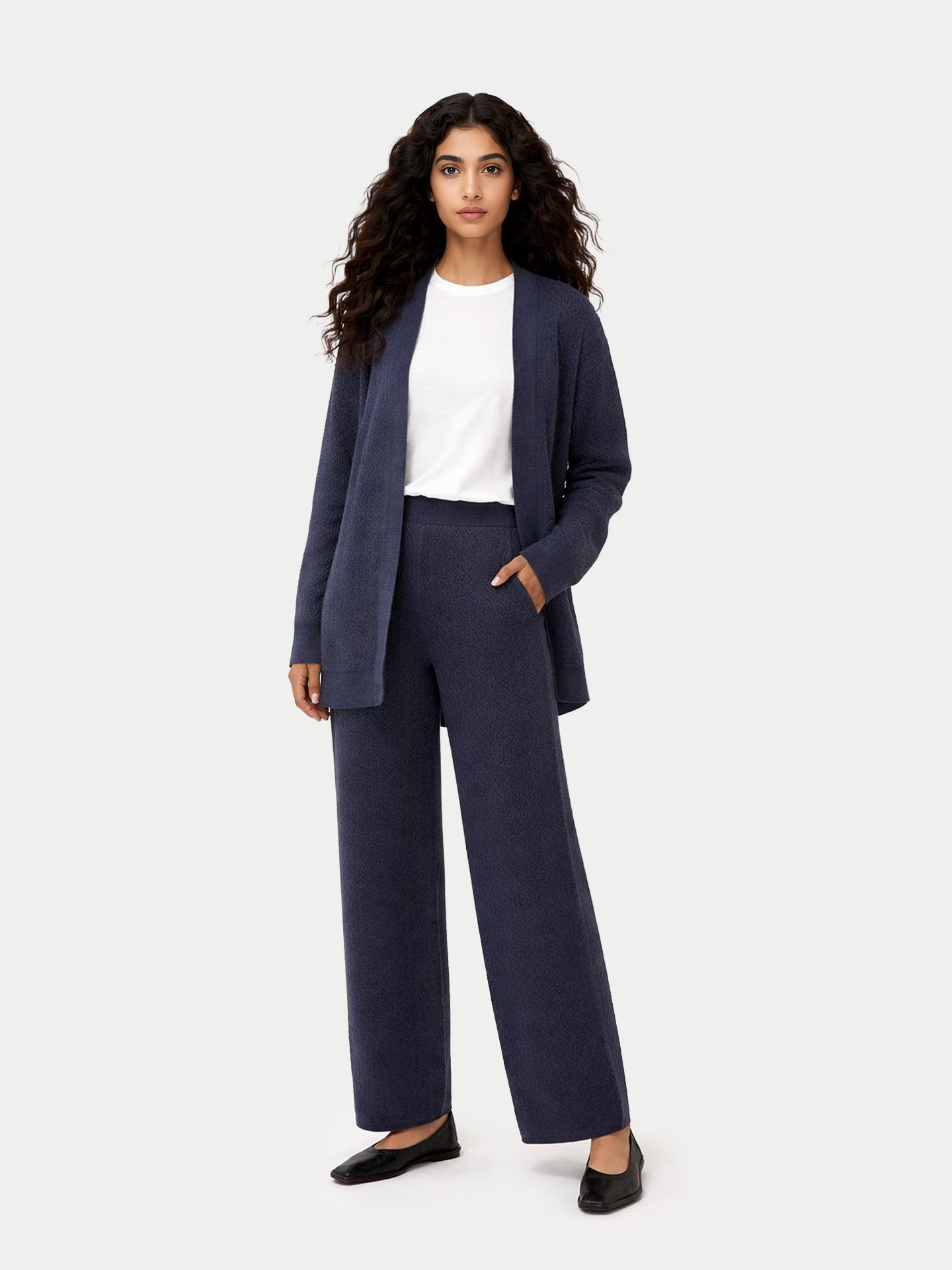 Vue de face d'une femme portant un cardigan bleu ouvert sur un t-shirt blanc et un pantalon large en maille côtelée assorti, sur fond gris clair. #color_bleu-courrone