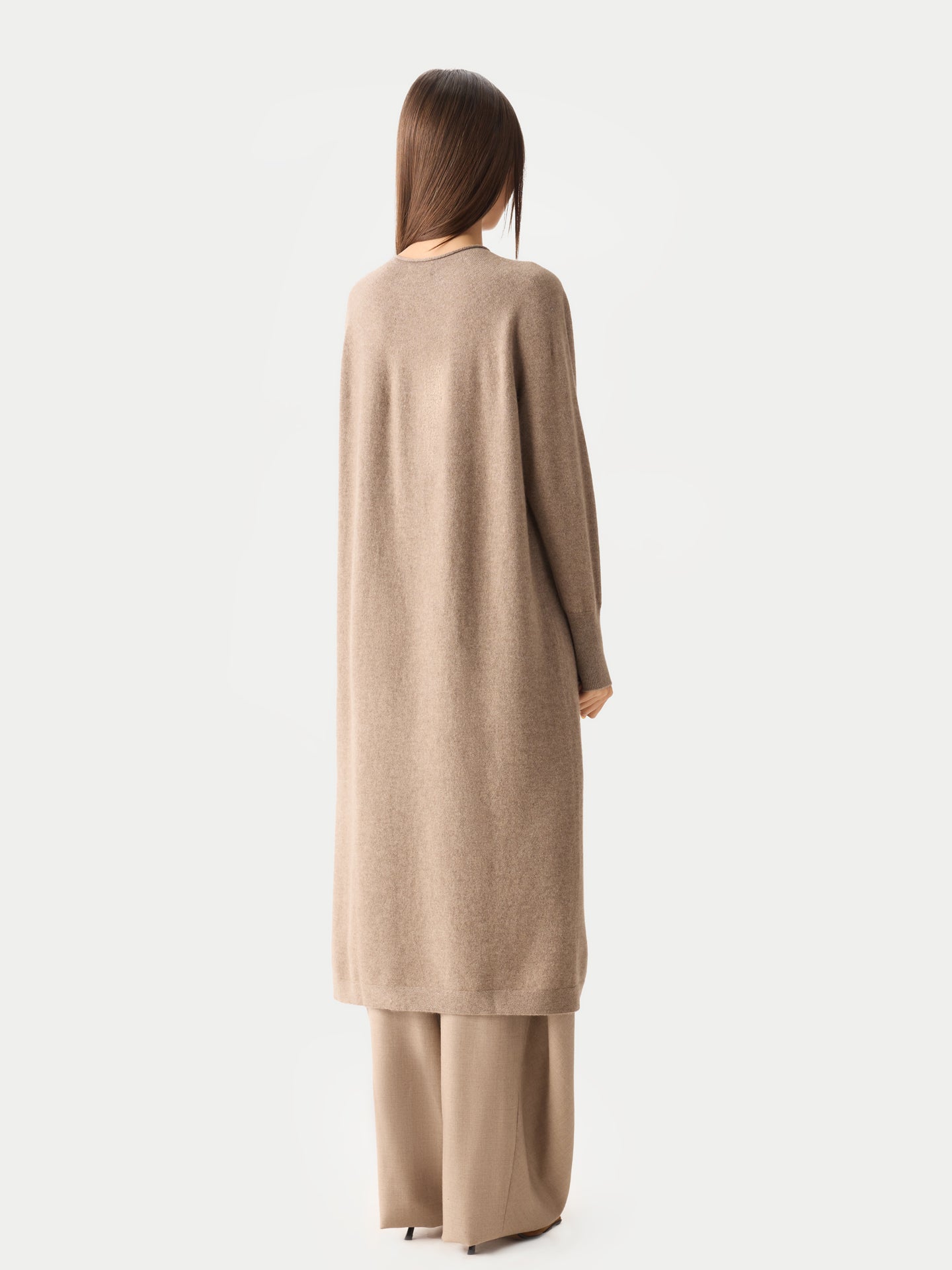 Vue de dos d'une femme portant une robe longue beige à col rond et manches longues fendue sur le côté, sur un pantalon beige, sur fond gris clair. #color_taupe