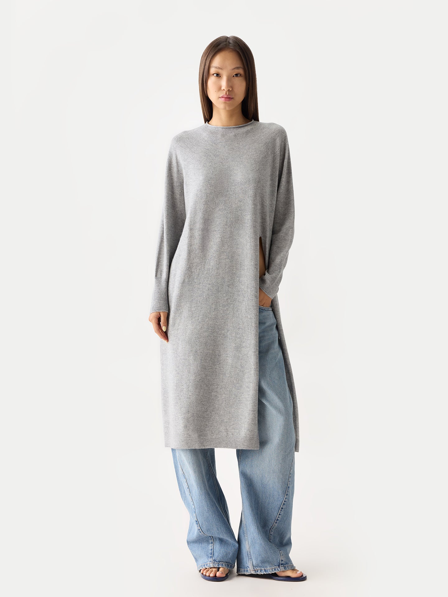 Vue de face d'une femme portant une robe gris clair à col rond, manches longues et fente latérale, sur un jean #color_high-rise