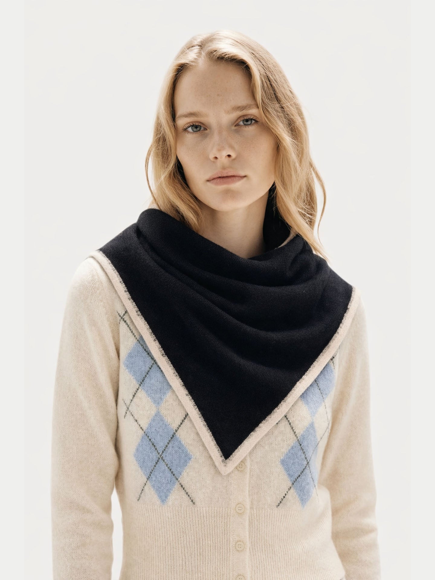close up front view of a Woman wearing a black scarf and beige sweater with argyle pattern on a white background.  #color_noir