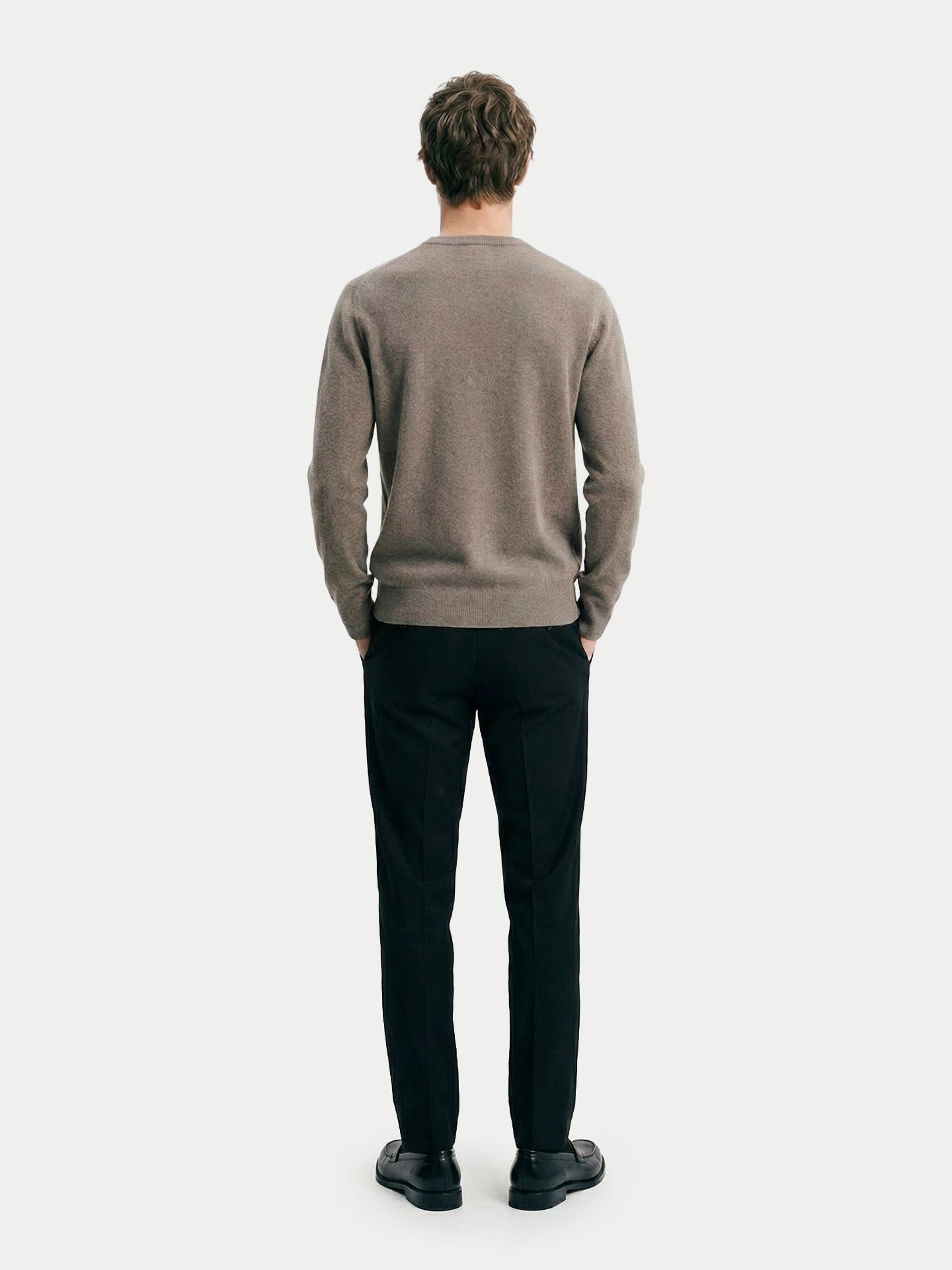 Vue de dos d'un homme portant un pull ras du cou taupe et un pantalon noir sur fond gris clair. #color_taupe