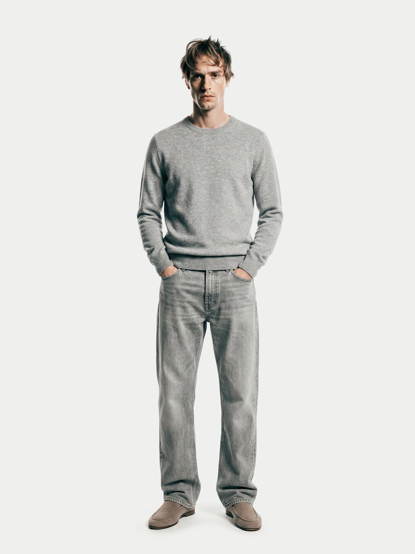 Vue de face d'un homme portant un pull gris à col rond et un jean sur fond gris clair. #color_high-rise