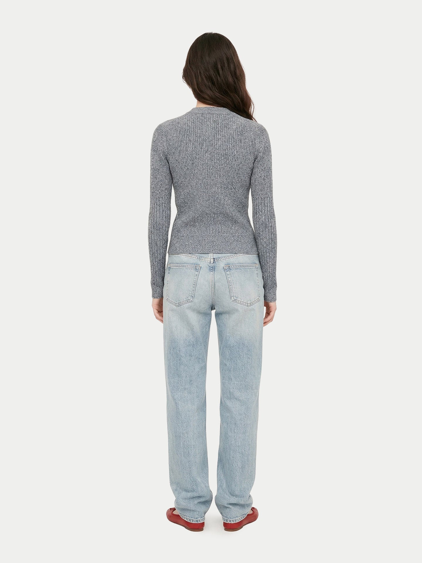 Vue de dos d'une femme portant un cardigan gris côtelé, un jean et des ballerines rouges sur un fond gris clair. #color_gris-pierre