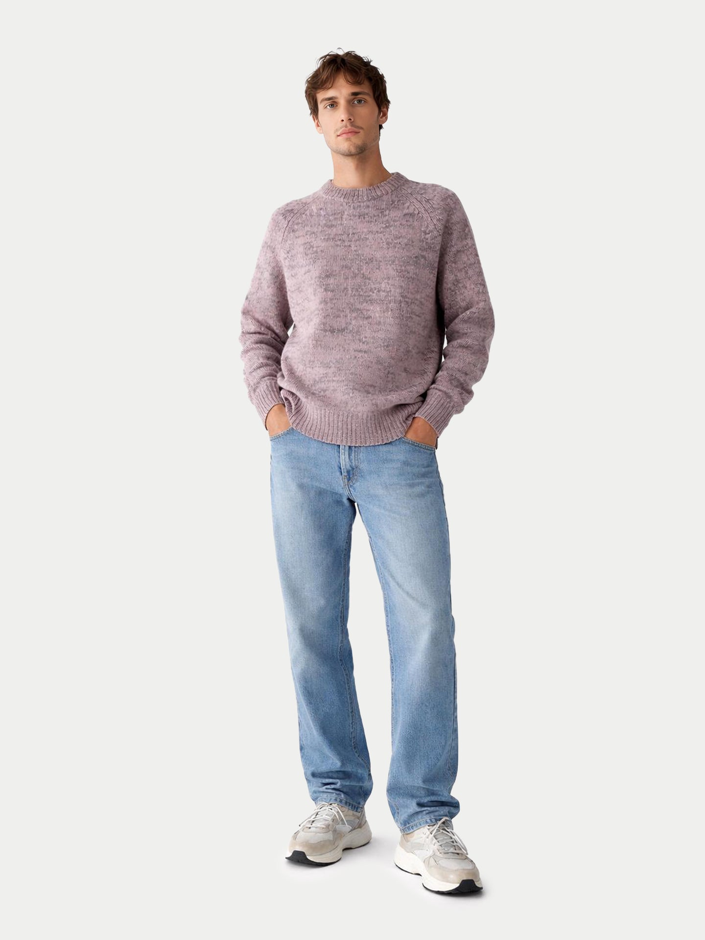 Vue de face d'un homme portant un pull à col rond rose-gris et un jean bleu sur fond gris clair. #color_rose-ivoire