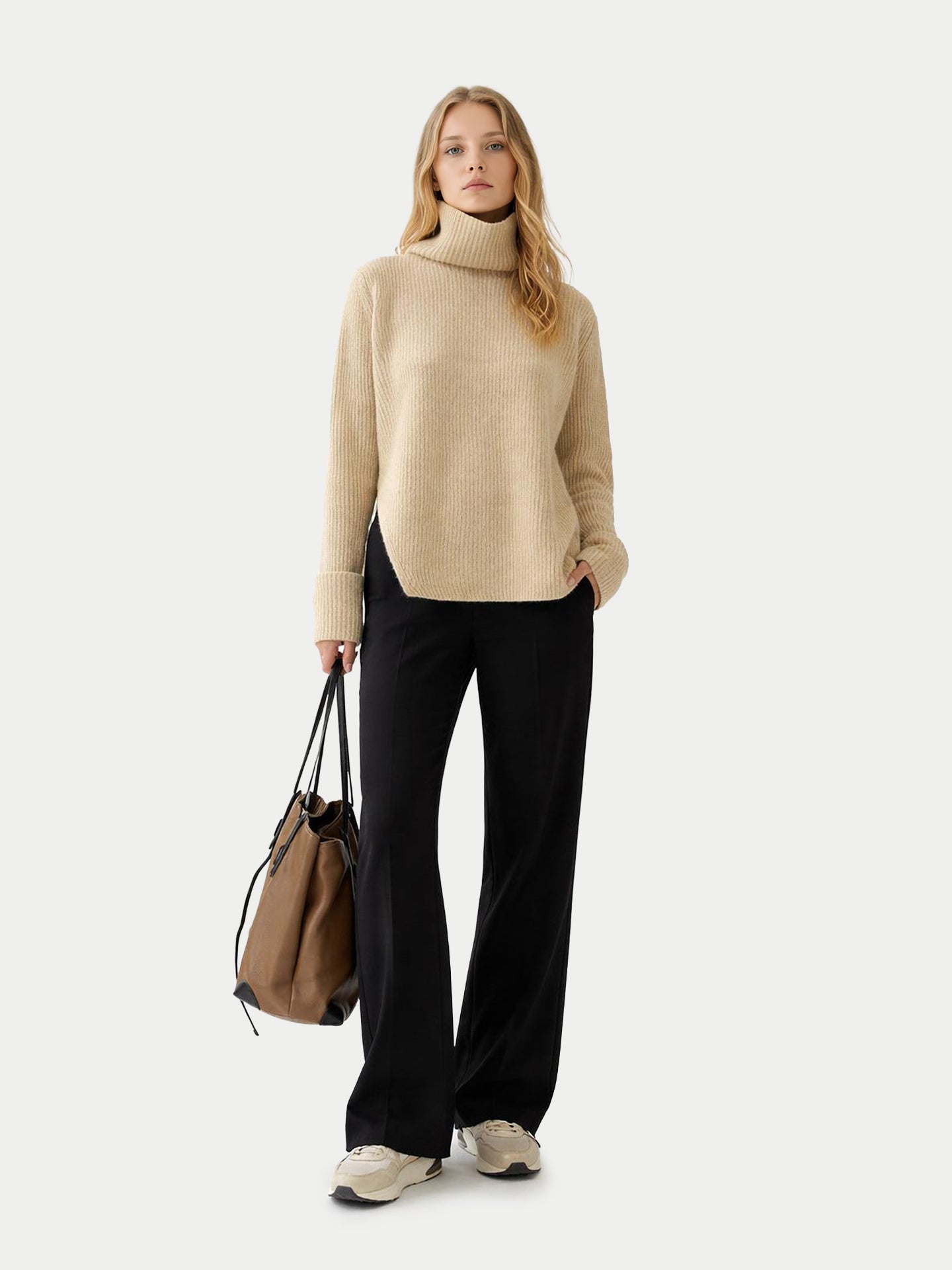 Vue de face d'une femme portant un pull beige côtelé à col roulé ample et manches retroussées, et un pantalon noir, sur fond gris clair. #color_beige