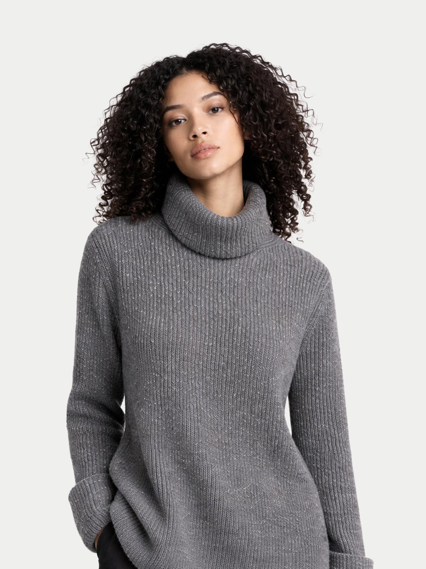 Gros plan de face d'un pull gris côtelé à col roulé ample sur fond gris clair. #color_gris-pierre