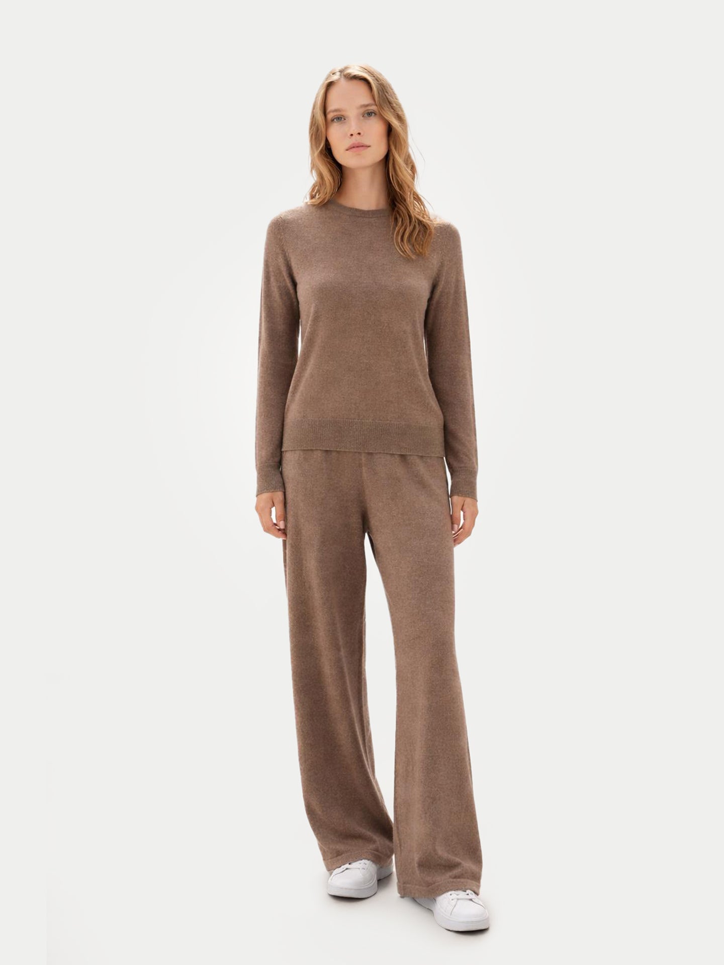 Vue de face d'une femme portant un pull marron à col rond assorti à un pantalon à jambes larges sur un fond gris clair. #color_taupe